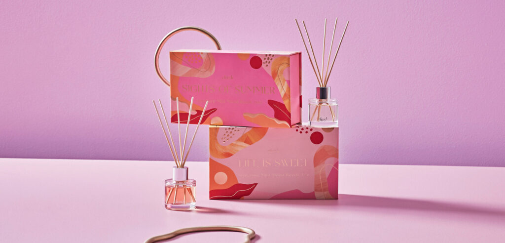 Candles and fragrance diffuser arranged on a pink background, highlighting dusk's modernised and vibrant brand presentation